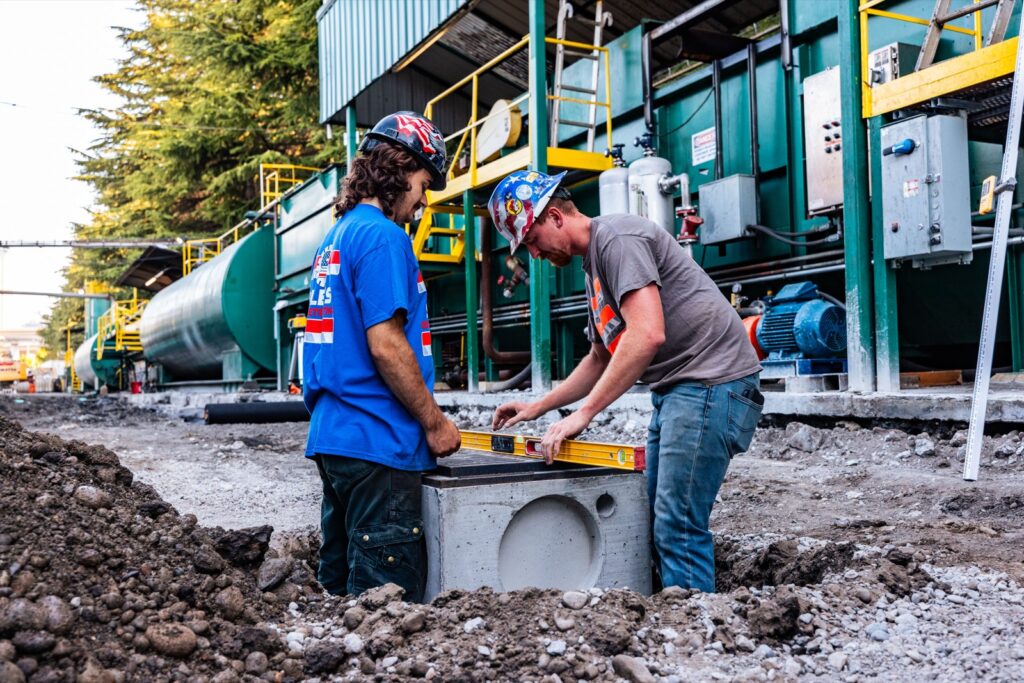 Two crew members setting a new catch basin in the regraded base